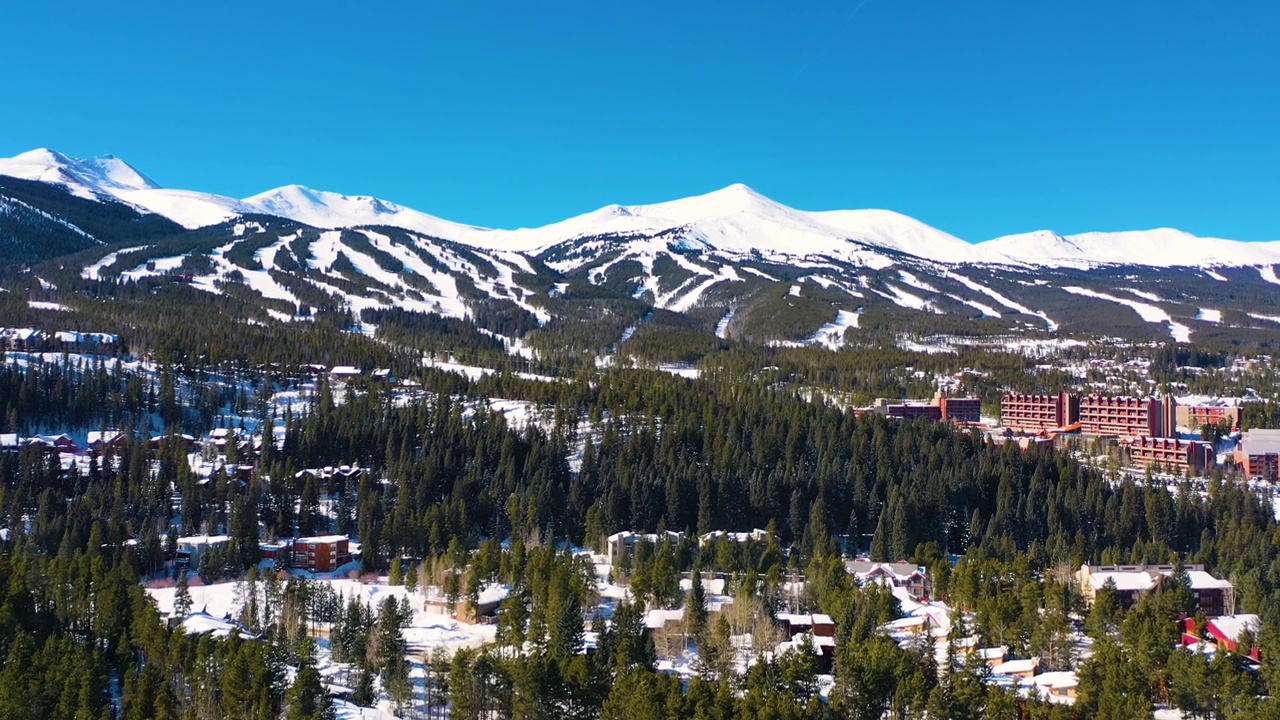 空中无人机在布雷肯里奇，科罗拉多州落基山腰滑雪斜坡的视频。山峰上有许多冬季运动的小径，覆盖着厚厚的粉雪视频素材