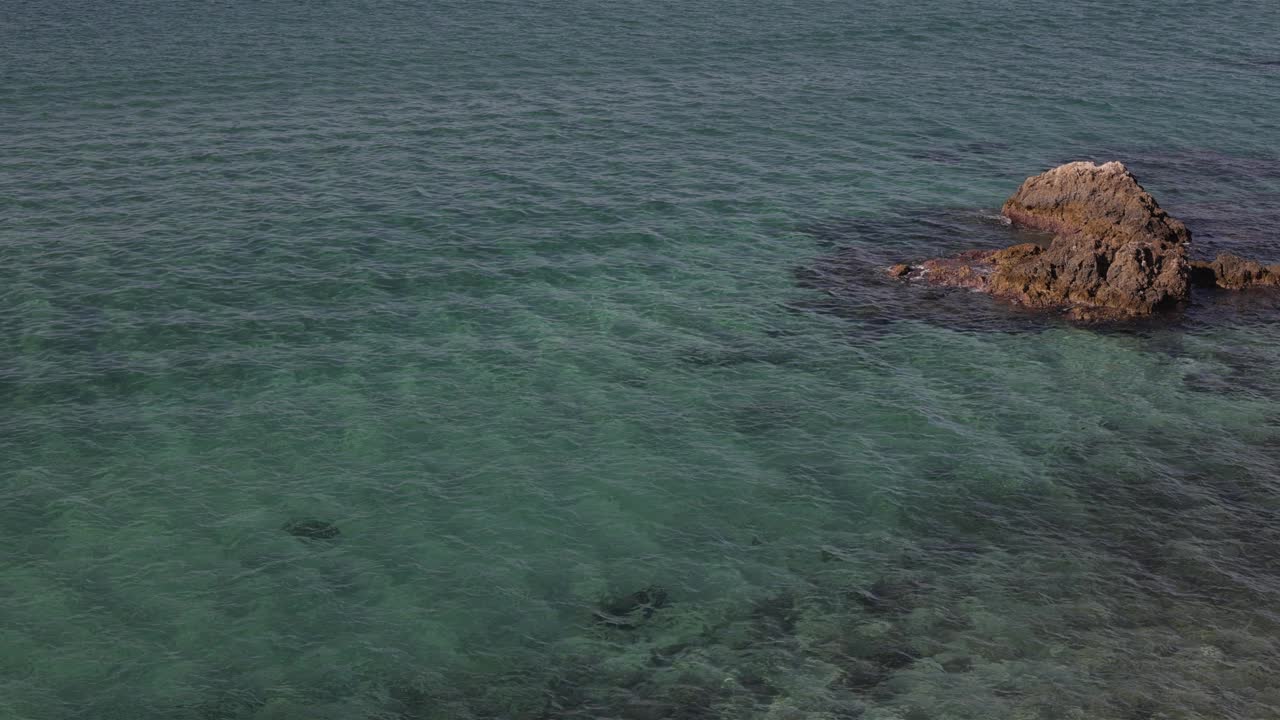 鸟瞰图，蓝色的海浪在底部的石头上视频下载