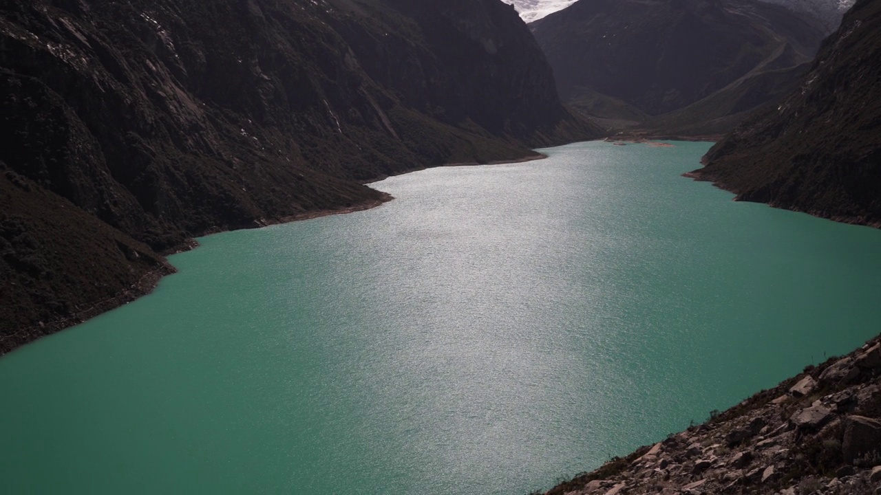 美丽的绿松石湖水在拉古纳帕隆泻湖在安第斯山脉的高山山脉在秘鲁华斯卡兰，雪山覆盖的山峰在一个明媚的阳光灿烂的一天。视频素材