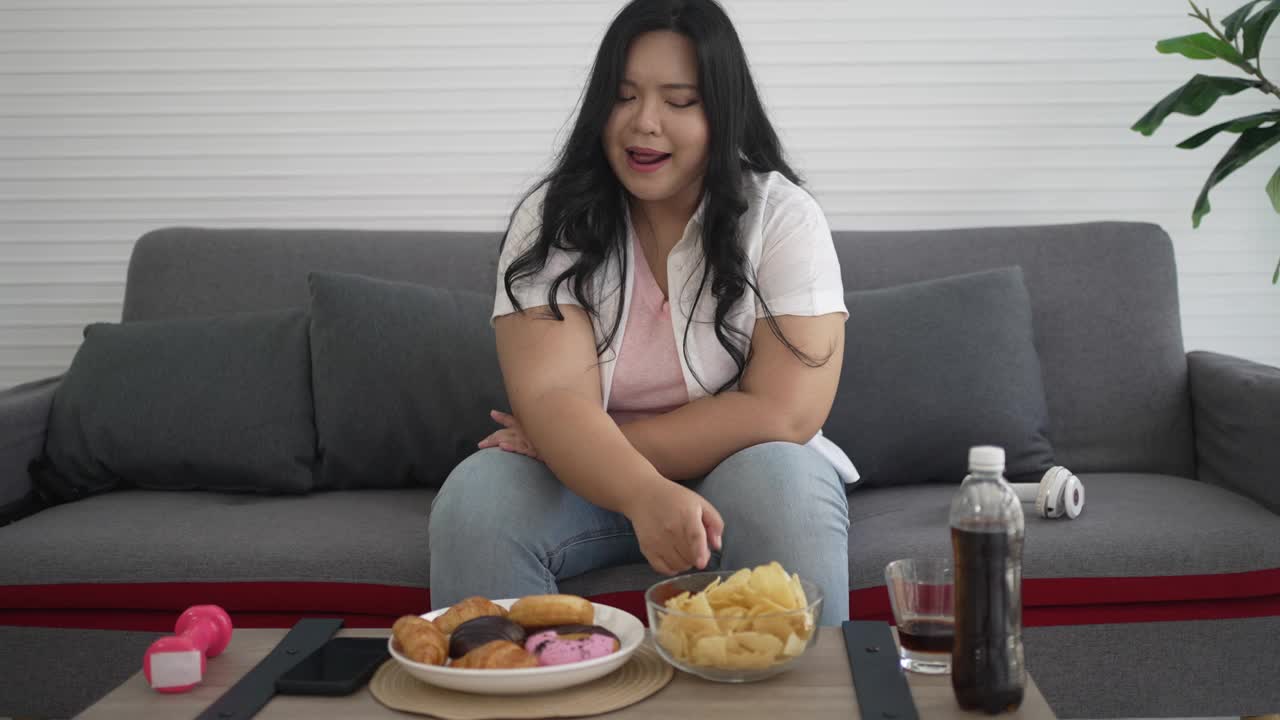 大码女人在吃垃圾食品。视频素材