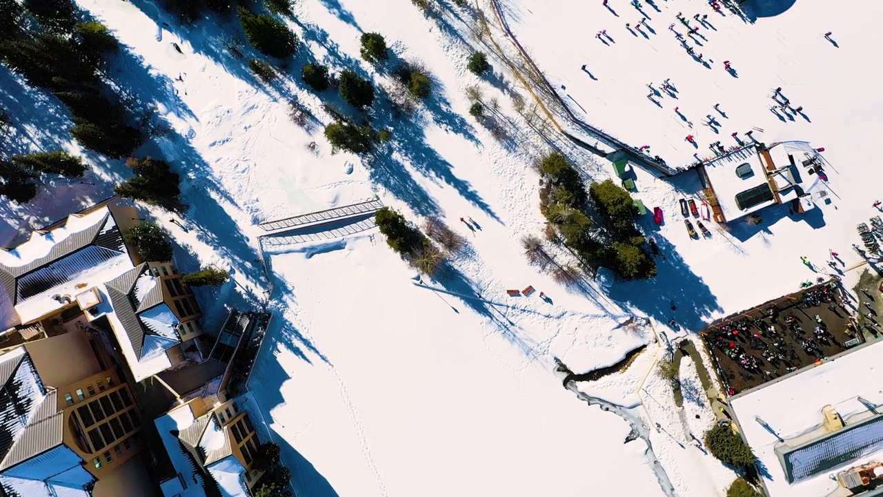 在寒冷的冬季雪道上，人们排队等待缆车滑雪和单板滑雪。无人机航拍图视频素材