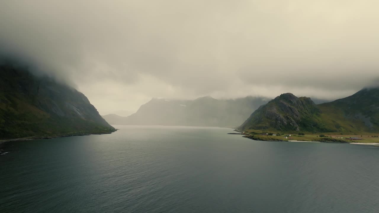 史诗般的全景广阔的水面之间的常绿北欧峡湾山峰，隐藏在雾。无人机的观点。视频素材