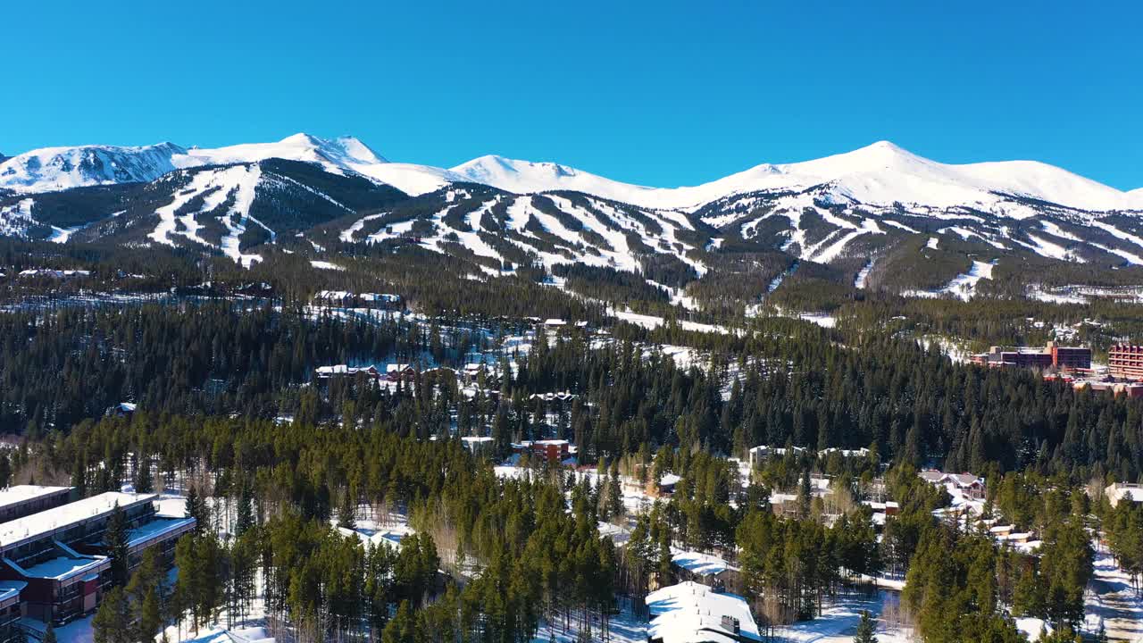 美丽的冰雪覆盖的冬季山峰与滑雪道空中无人机视图准备在厚厚的松树林中进行户外运动和冒险视频素材