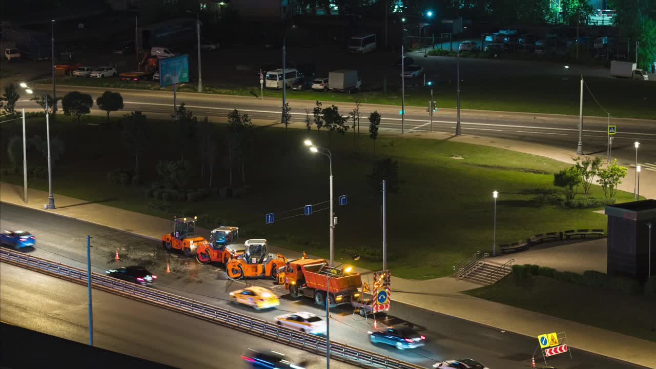 时间流逝。夜晚的城市。几台大型沥青压路机在繁忙的高速公路上工作。高角度视图视频下载