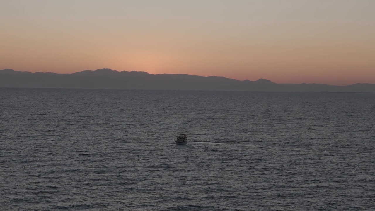 一艘小帆船穿越地中海，驶向橘黄色的夕阳地平线视频素材