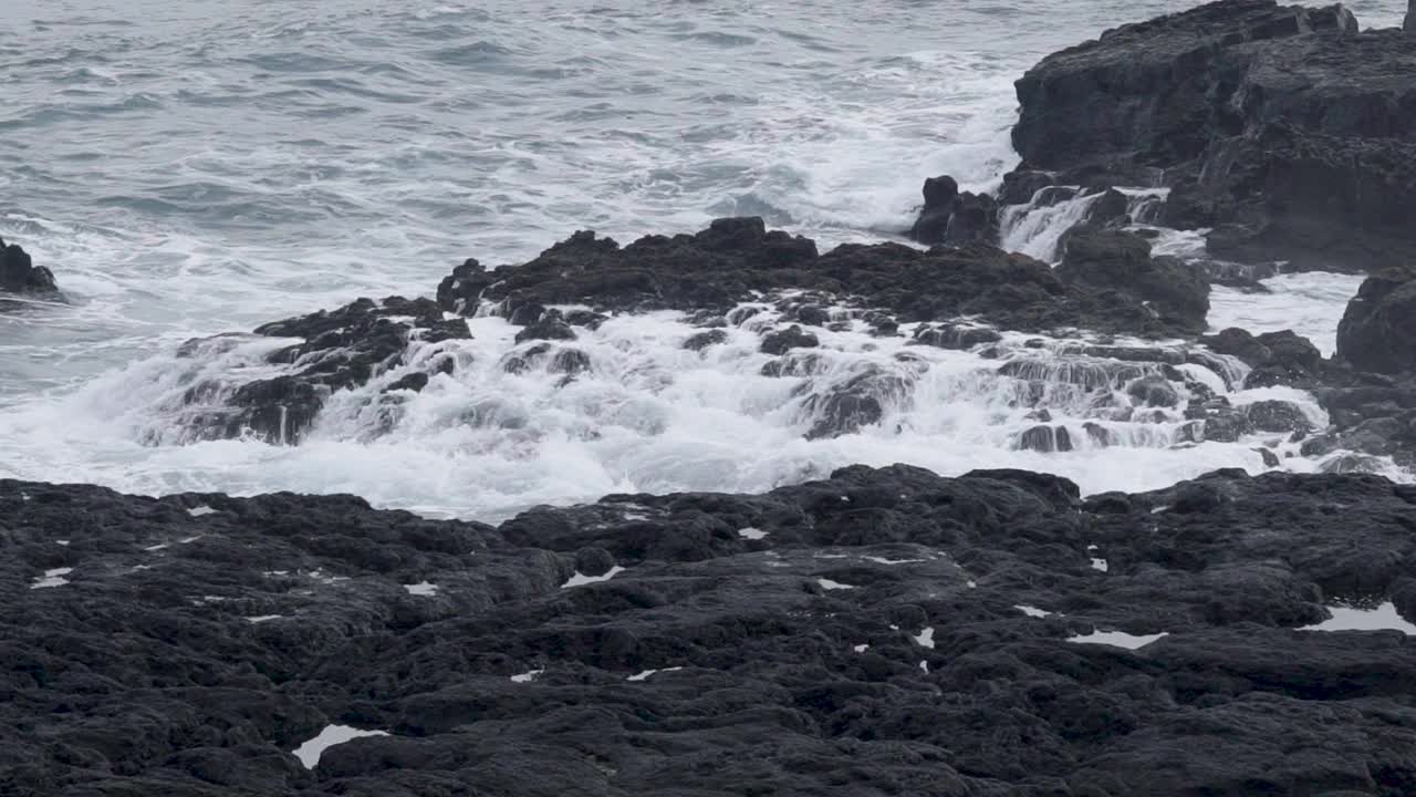 海浪拍打着冰岛黑色沙滩上的岩石海岸线视频素材