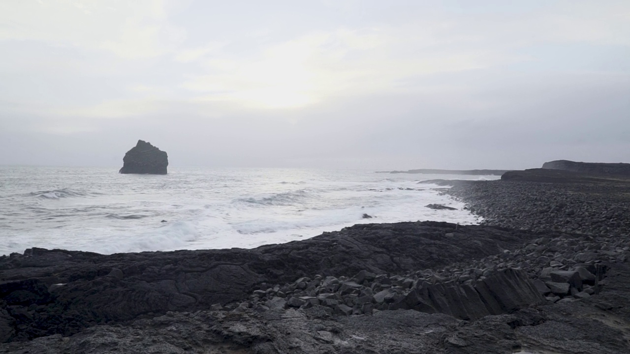 海浪拍打着冰岛黑色沙滩上的岩石海岸线视频素材