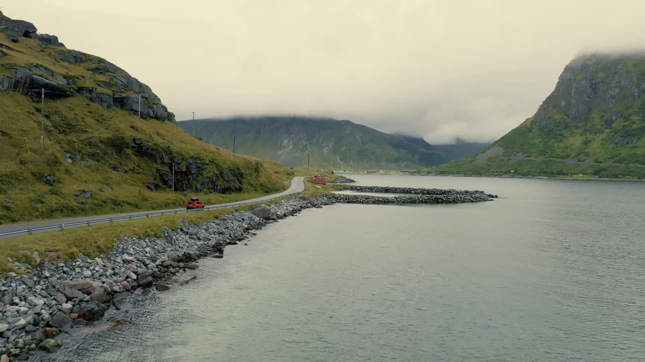 全景的沿海道路在史诗峡湾景观。红色SUV在路上行驶。视频素材