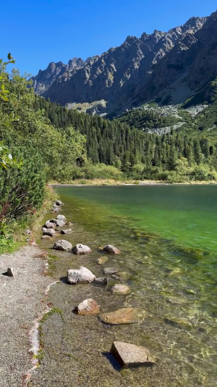 一个美丽的湖，清澈的水和山在一个晴朗的晴天的背景。视频素材