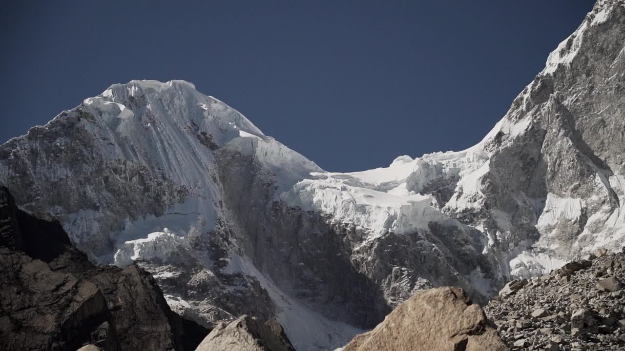 在秘鲁华斯卡兰的白科迪勒拉安第斯山脉的高山上，拉古纳帕隆泻湖的一座金字塔形山的冰川被冰雪覆盖，阳光明媚的日子里，山峰被白雪覆盖。视频素材