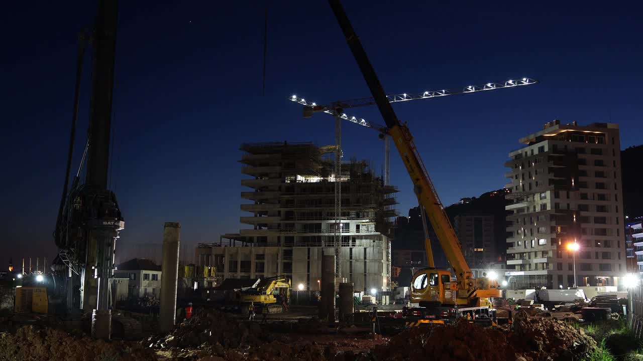 夜间，照明塔式起重机在建筑工地工作视频下载