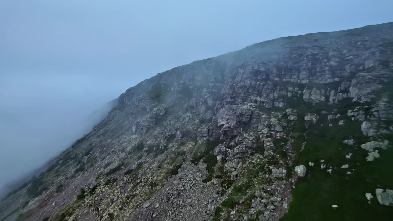 空中拍摄了陡峭的悬崖和灰色的岩层，雾气揭示了山脊和日出视频素材