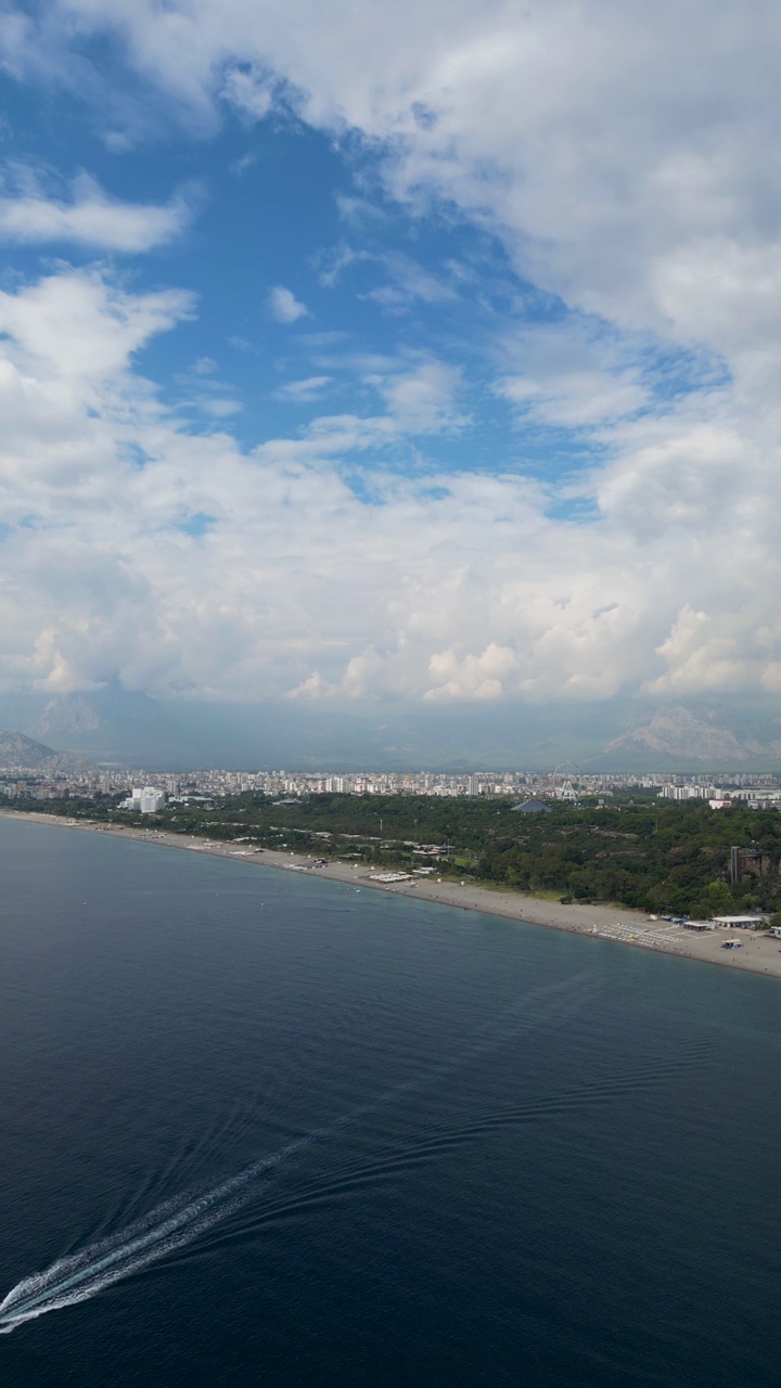 鸟瞰土耳其安塔利亚的konyaaltai海滩。一群人在海里游泳，在海滩上晒日光浴。雄伟的山脉与阴霾的背景。在土耳其度假视频素材