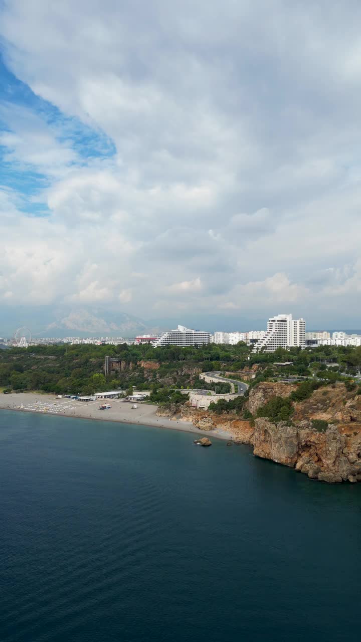 鸟瞰土耳其安塔利亚的konyaaltai海滩。一群人在海里游泳，在海滩上晒日光浴。雄伟的山脉与阴霾的背景。在土耳其度假视频素材