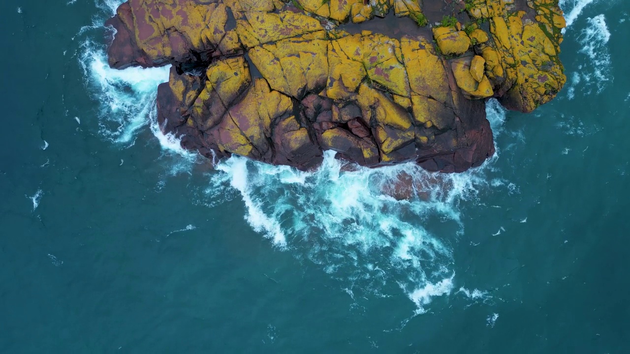 无人机拍摄的白天海浪冲击海岸岩层的画面视频素材