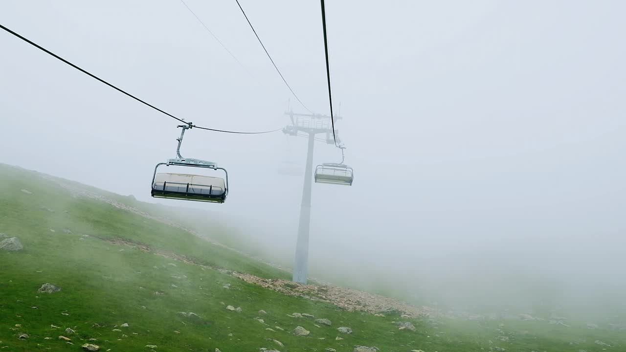 在被遗弃的滑雪电梯上，浓雾中没有人移动的空缆车视频素材