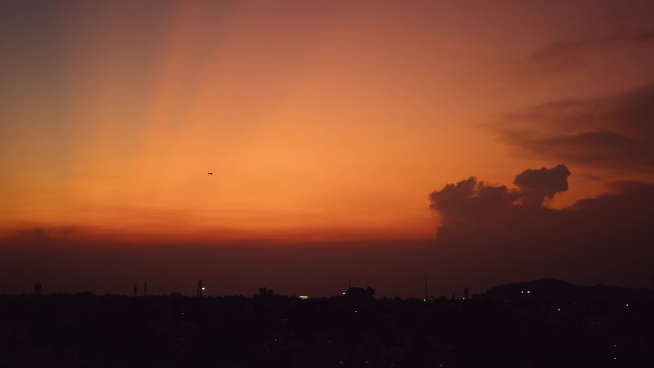 鸟群在日落时与天空中橙色的云一起飞行的慢动作镜头，鸟群在橙色天空中飞行的日落美景。视频素材