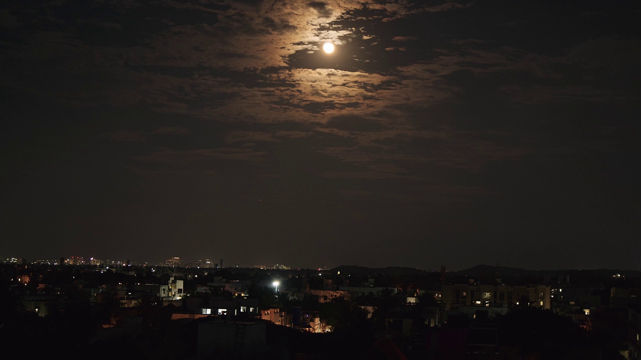 夜景中的月亮、云彩和城市风景。视频下载