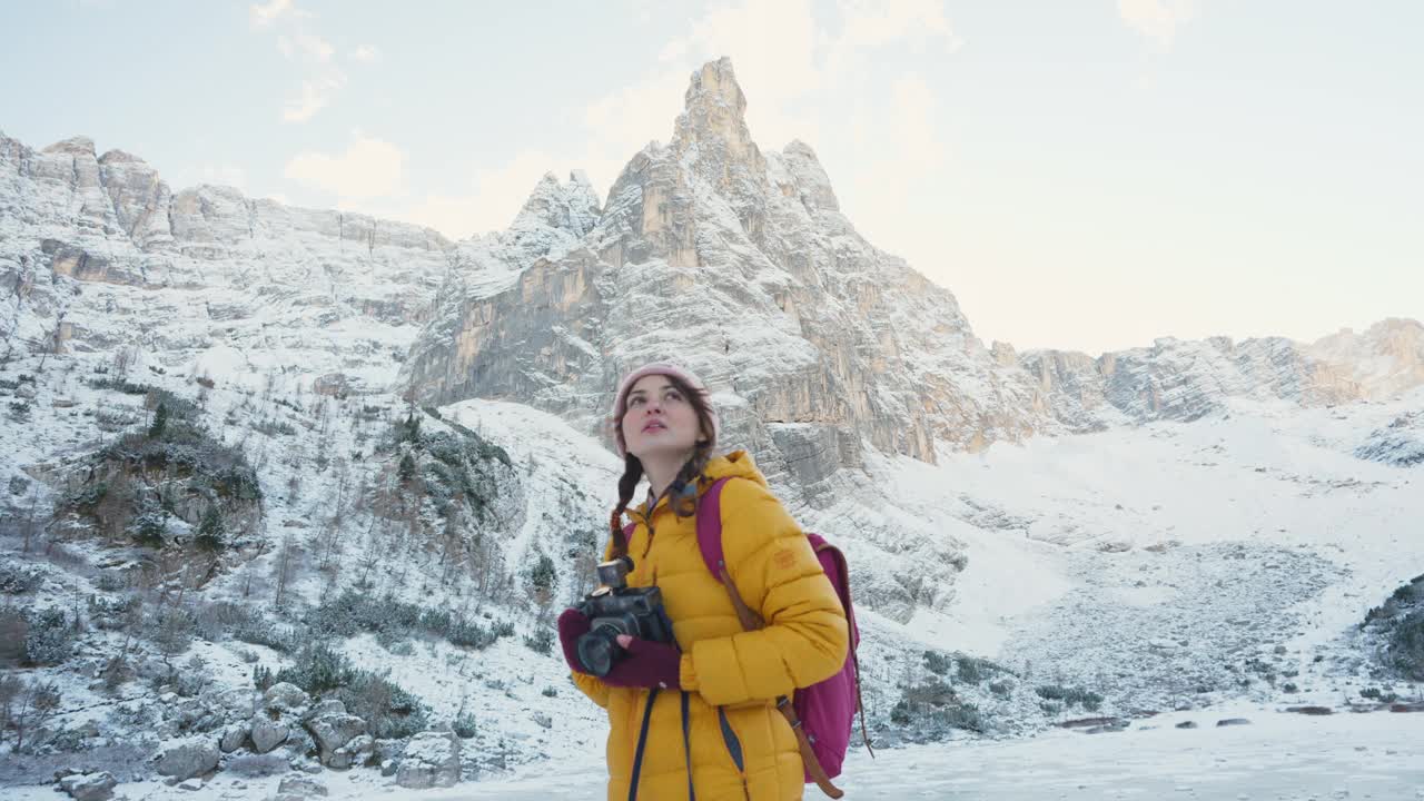 冬天，一名妇女带着相机在白雪覆盖的白云岩徒步旅行视频素材