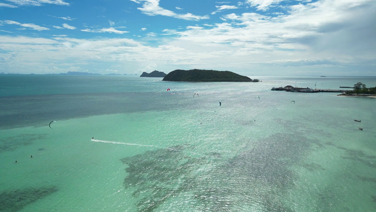 在泰国帕颜岛，风筝冲浪者在蓝绿色的海面上飞行。无人机轨道拍摄视频素材