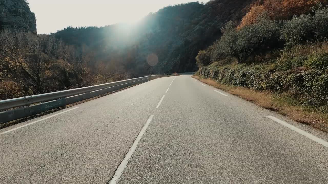 在蓝天和地平线的背景下，在一条长长的柏油直路上开车。旅游和交通的概念。山区国家公园。开车到目的地。节日假期。视频素材