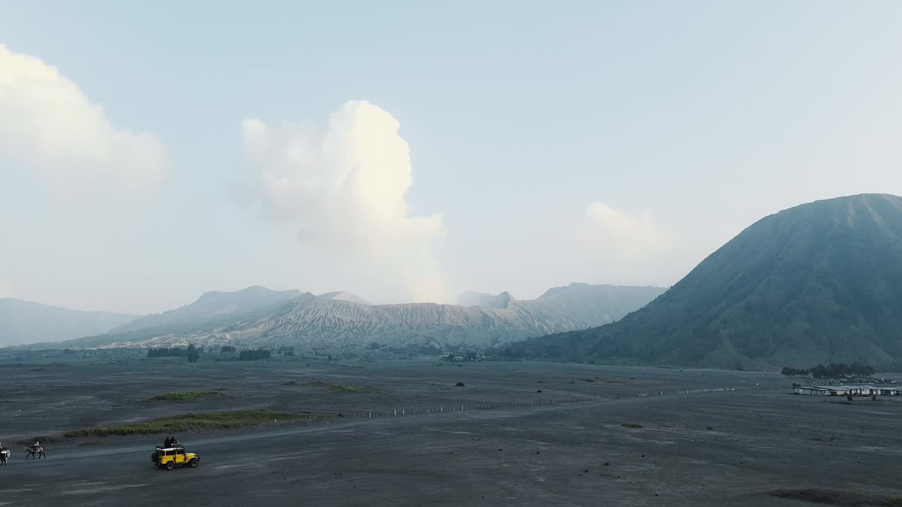 无人机拍摄的印尼布罗莫火山附近的沙漠，一辆吉普车骑在沙滩上。视频素材