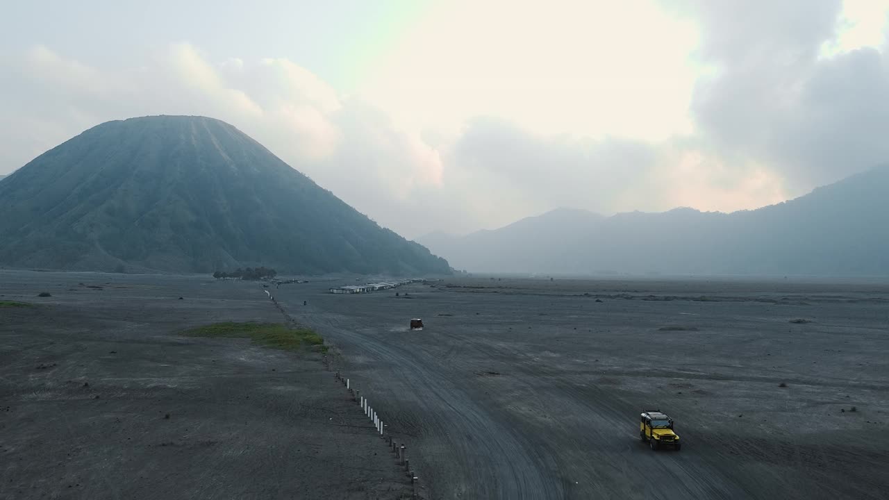 无人机拍摄的印尼布罗莫火山附近的沙漠，一辆吉普车骑在沙滩上。视频素材