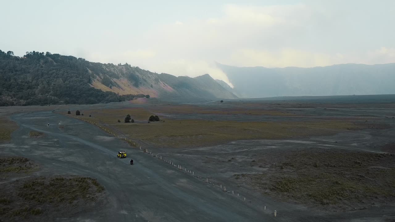 无人机拍摄的印尼布罗莫火山附近的沙漠，一辆吉普车骑在沙滩上。视频下载