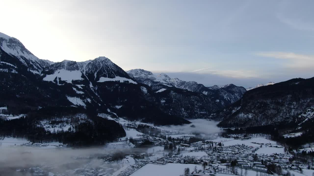 早晨在山上覆盖着雪和树，雾气笼罩着村庄，4k视频素材