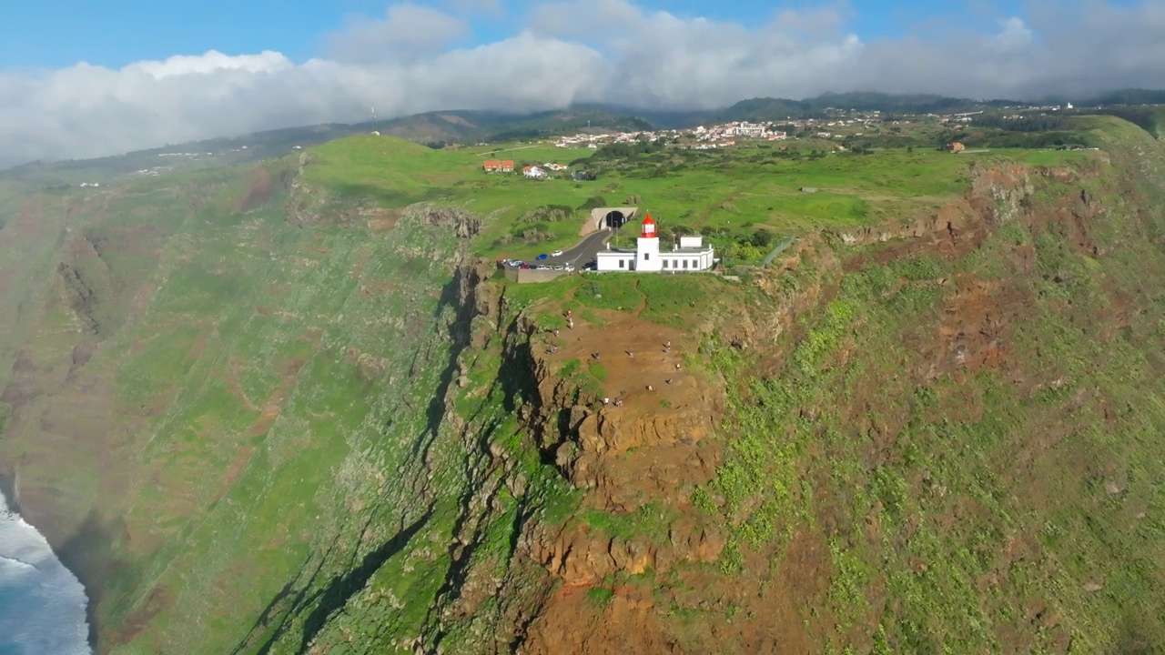 Ponto do Pargo灯塔坐落在绿色的小山上，下面是海浪视频素材