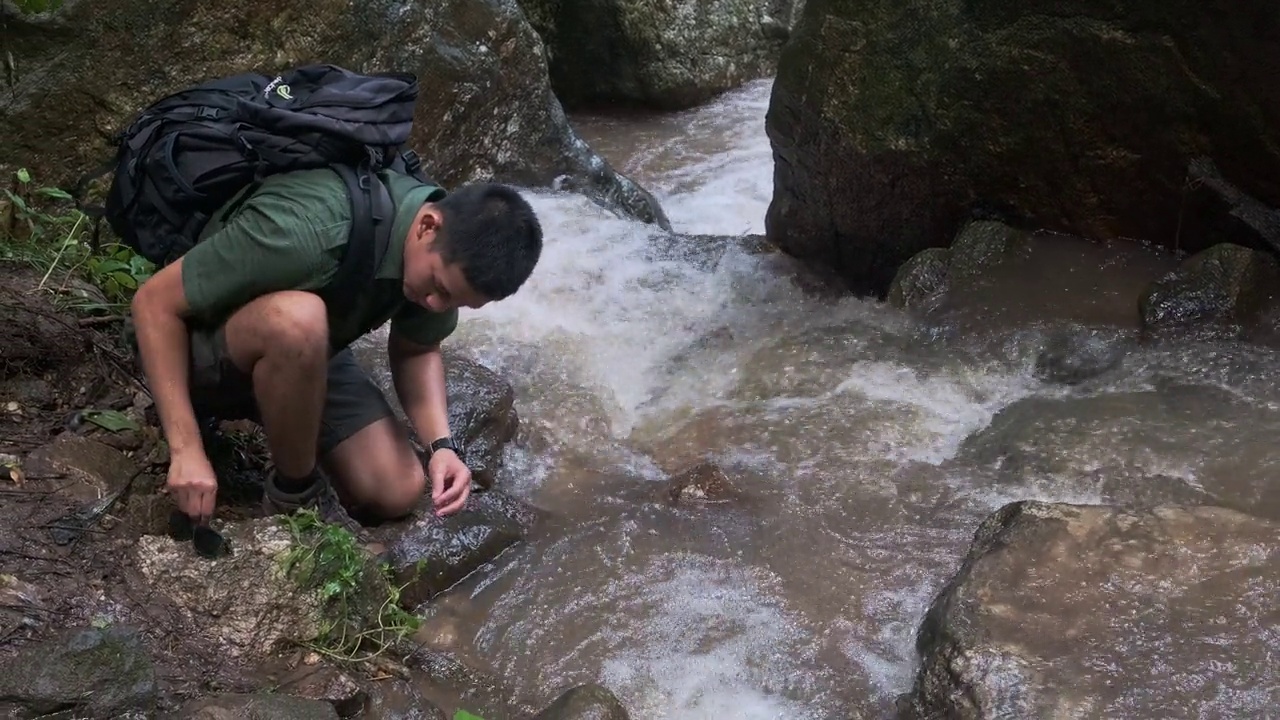 男旅行者用山间小溪的冷水洗手。视频素材