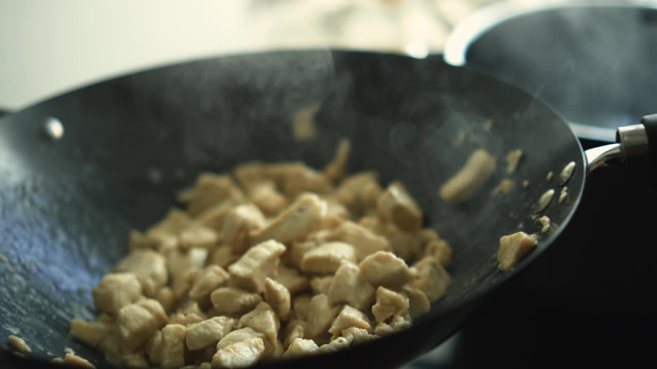 800帧/秒的高速烹饪动作-在厨房炉子上的热锅里搅拌鸡肉块，准备食物视频素材