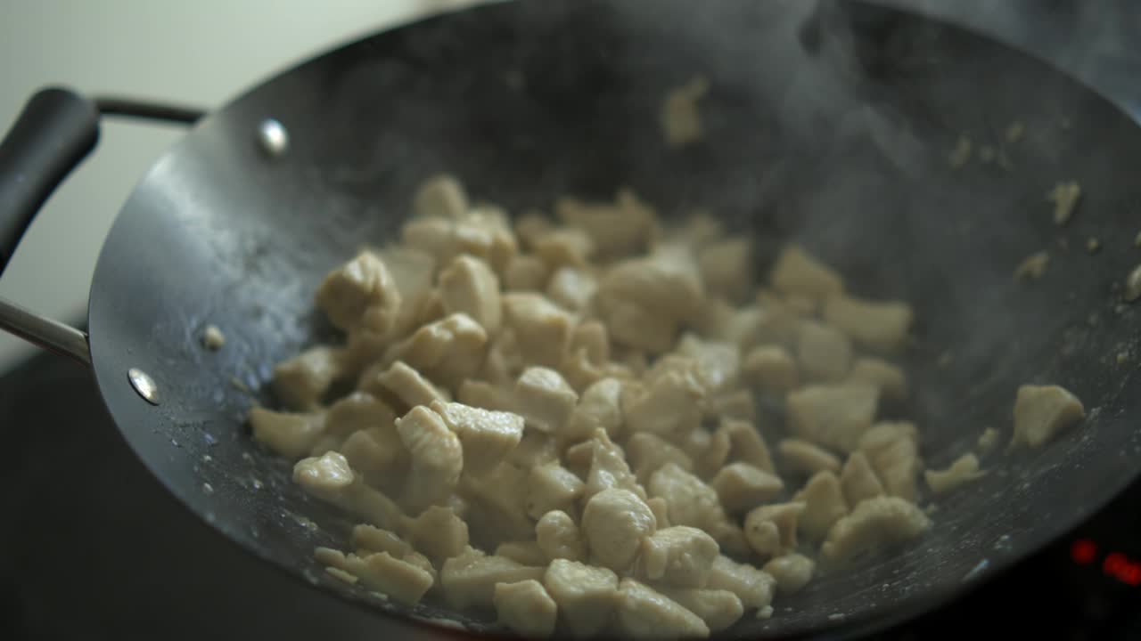 鸡块在滋滋作响的平底锅中翻炒，800fps烹饪鸡肉在热锅中搅拌视频素材