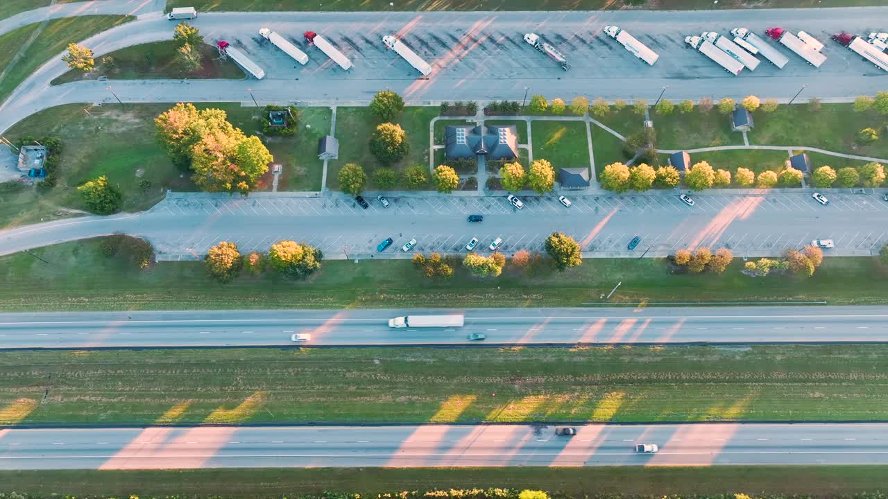 在繁忙的美国州际高速公路附近有休息区的大型卡车停靠站，有快速行驶的汽车和卡车。州际旅行期间的休闲停车场视频素材