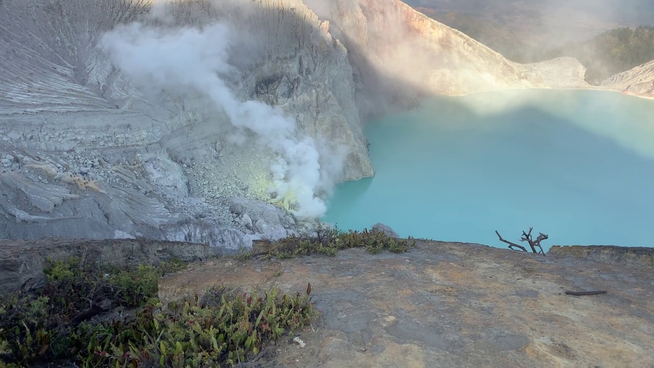 日出后，卡瓦伊真火山口火山的岩石悬崖与绿松石硫磺湖水。印尼东爪哇的旅游景点。自然景观背景。视频下载