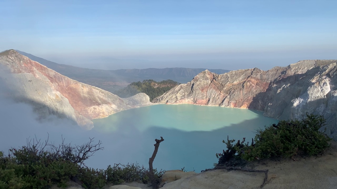 日出后，卡瓦伊真火山口火山的岩石悬崖与绿松石硫磺湖水。印尼东爪哇的旅游景点。自然景观背景。视频素材