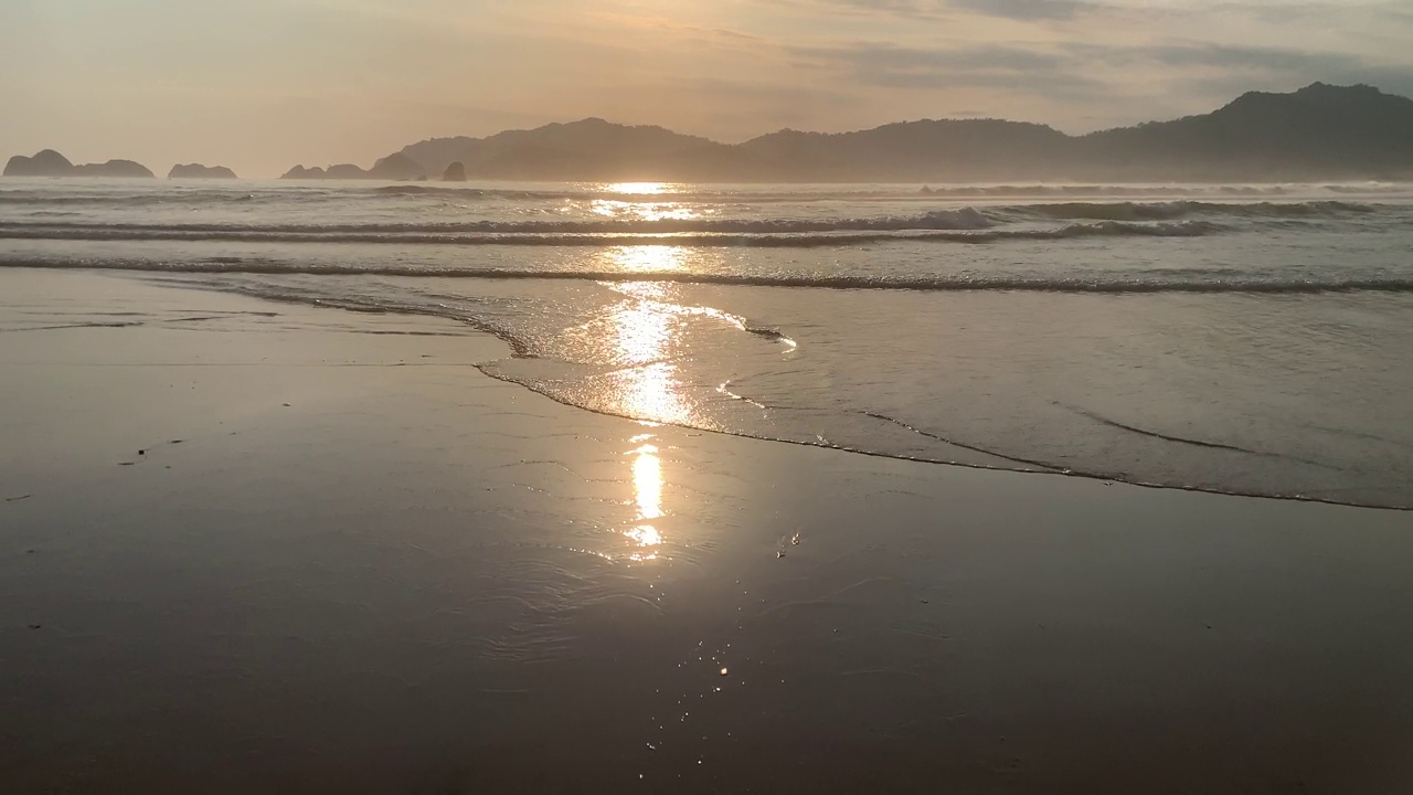 夕阳越过海浪冲刷沙滩。热带没有自然海景。红岛海滩，班尤旺吉，东爪哇，印度尼西亚。视频下载