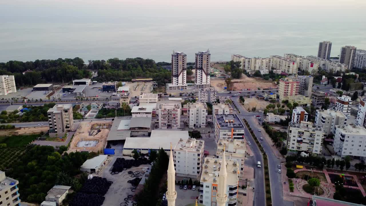 一座有两座尖塔的小清真寺，位于城市中心，以日落时的大海为背景。这张照片是从一架无人机上拍摄的，它正在离开一座有两座尖塔的清真寺。伊斯兰教的概念视频素材