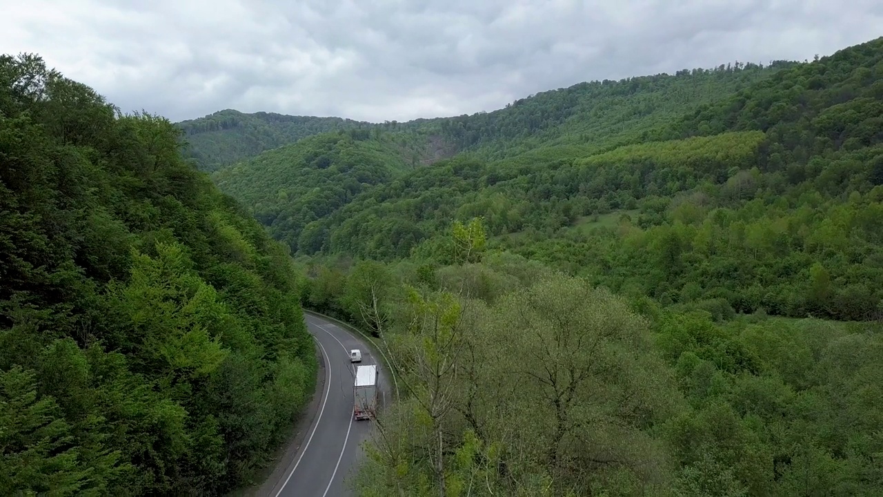 汽车行驶在喀尔巴阡山脉的乡村道路上，用空中无人机摄像机拍摄视频素材