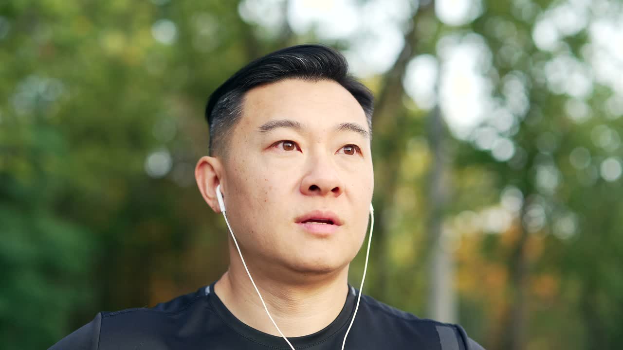 快乐的亚洲运动员在晨跑后闭着眼睛站在城市公园放松的特写。视频素材