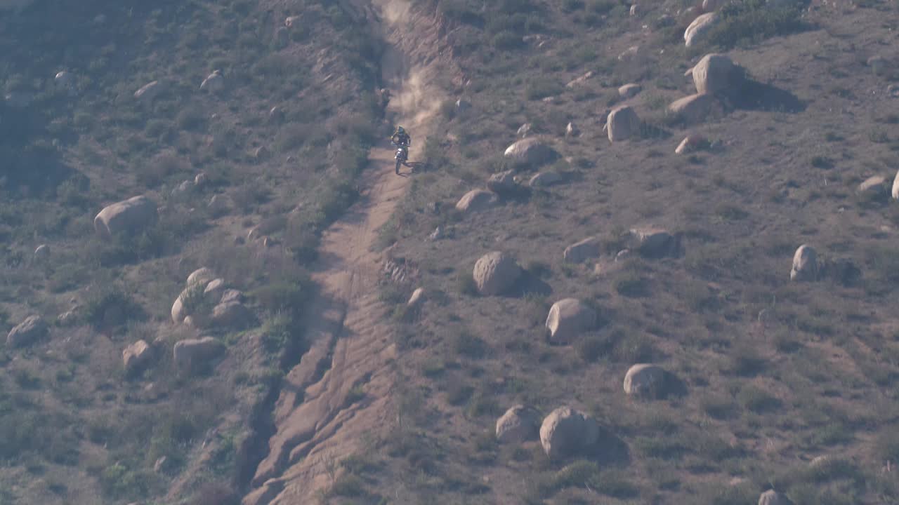 在下墨西哥沙漠山区的土路上骑摩托车的航拍照片视频下载