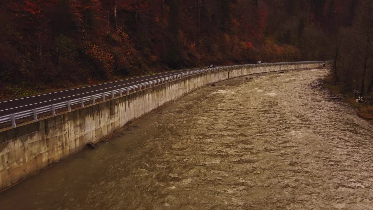 一辆汽车在靠近秋天森林的道路上行驶的鸟瞰图视频素材