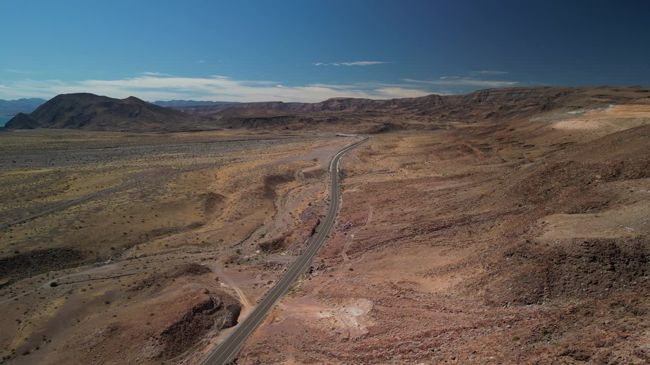 在墨西哥下加利福尼亚5号高速公路上，汽车行驶在红色火山沙漠景观中的高空航拍视频下载