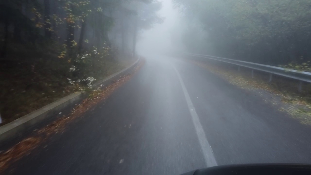 在雾蒙蒙的森林里开车。从相机拍摄的视角行驶在空旷危险的柏油路在秋天视频素材