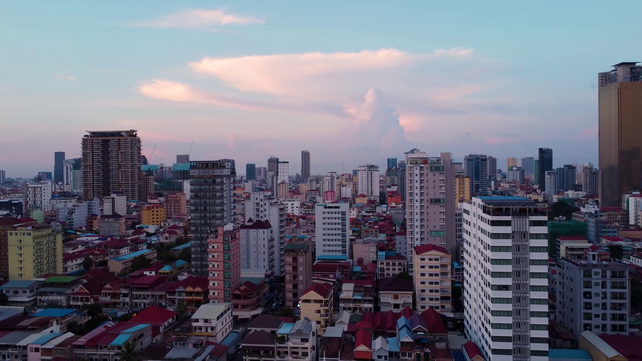 这是夕阳西下时，从无人机向左转俯瞰柬埔寨首都金边的鸟瞰图。远处可见巨大的风暴云。视频素材