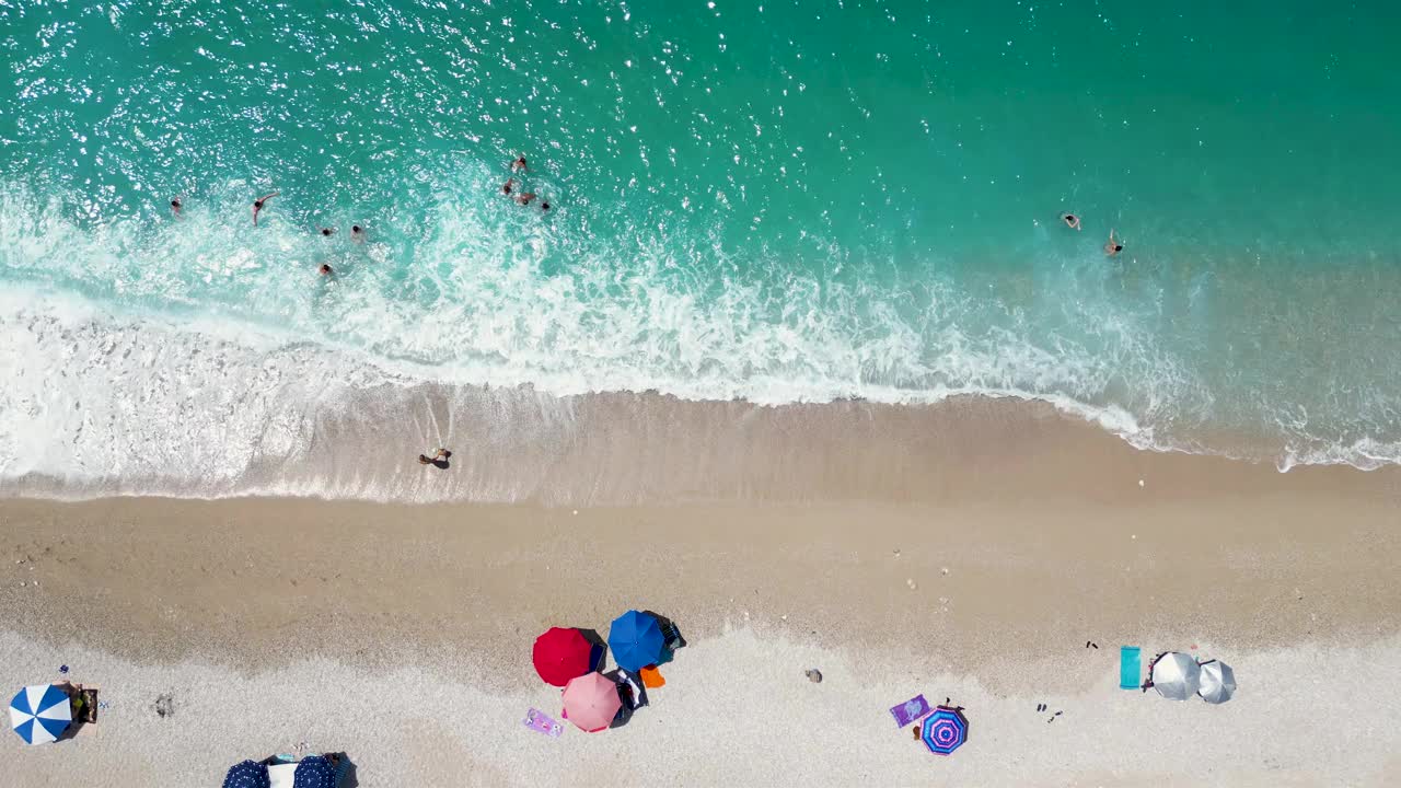 全景空中无人机美丽的海滩，人们在水里玩耍，在岸边放松视频素材