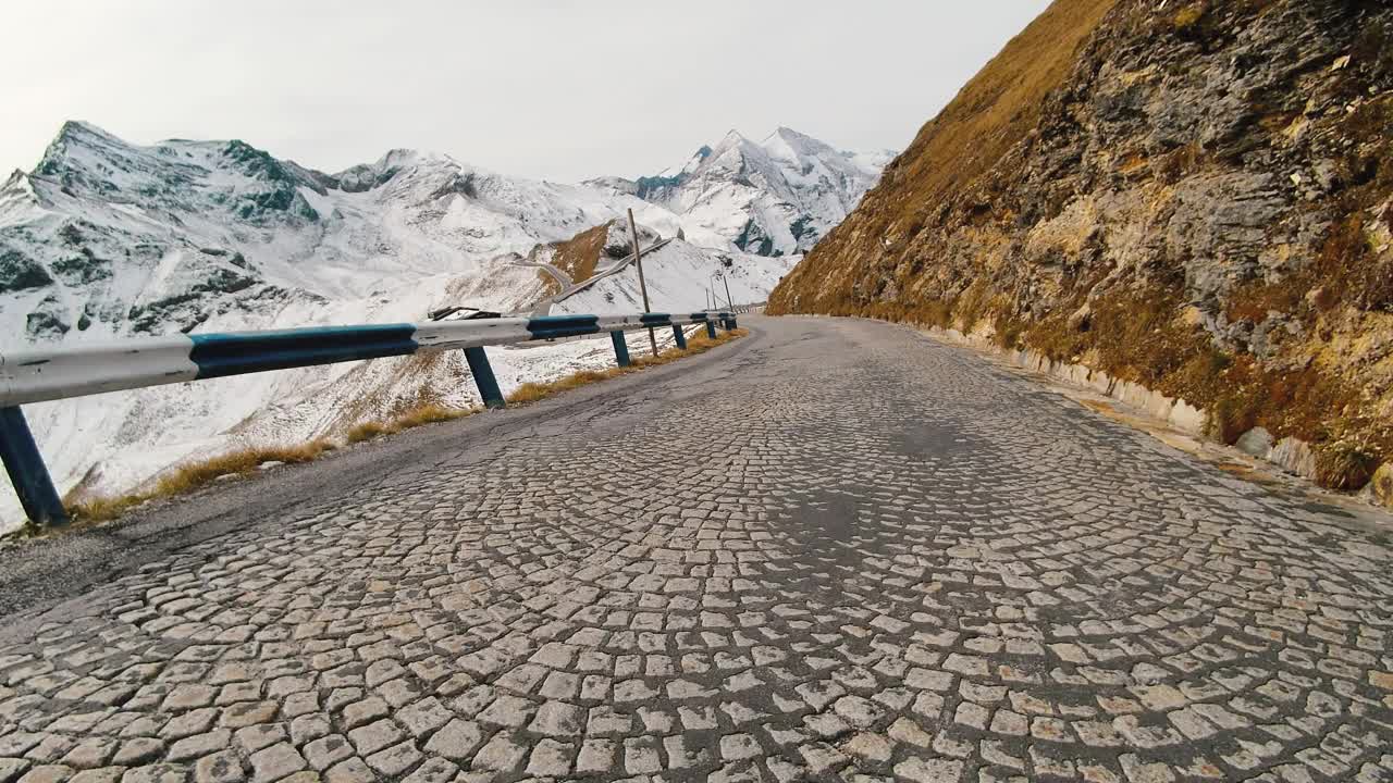 乘车观景，雄伟的大格洛克纳山路在奥地利，积雪覆盖了陡峭的高山山峰。跑车或自行车沿着奥地利阿尔卑斯山脉雄伟美丽的山路行驶视频素材