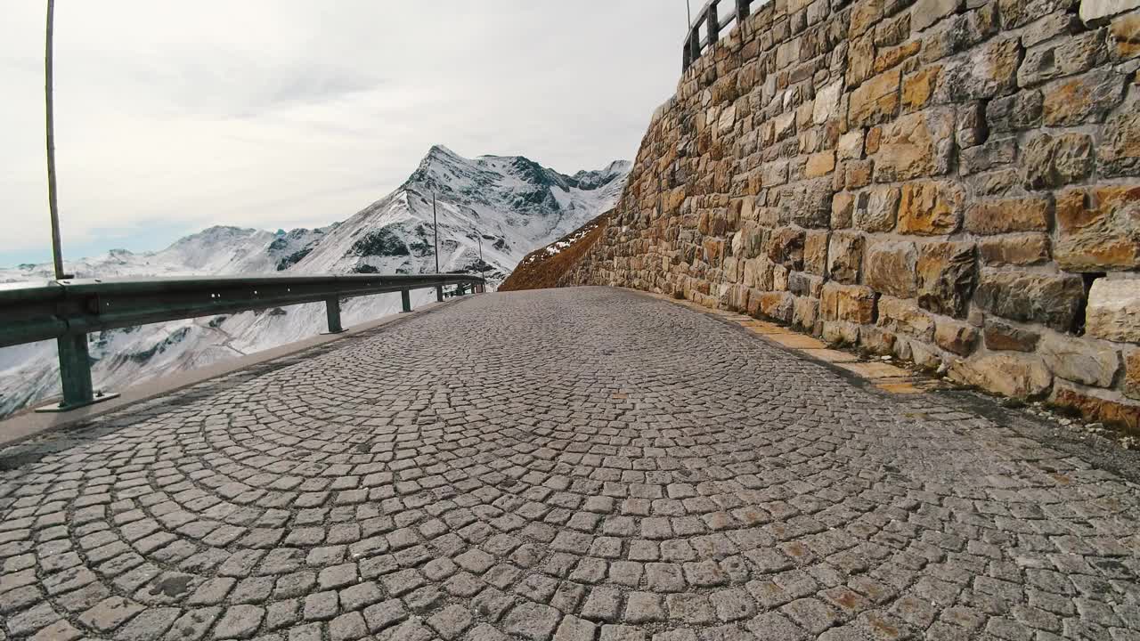 乘车观景，雄伟的大格洛克纳山路在奥地利，积雪覆盖了陡峭的高山山峰。跑车或自行车沿着奥地利阿尔卑斯山脉雄伟美丽的山路行驶视频素材