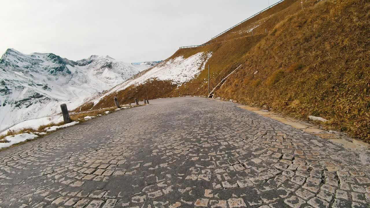 乘车观景，雄伟的大格洛克纳山路在奥地利，积雪覆盖了陡峭的高山山峰。跑车或自行车沿着奥地利阿尔卑斯山脉雄伟美丽的山路行驶视频素材