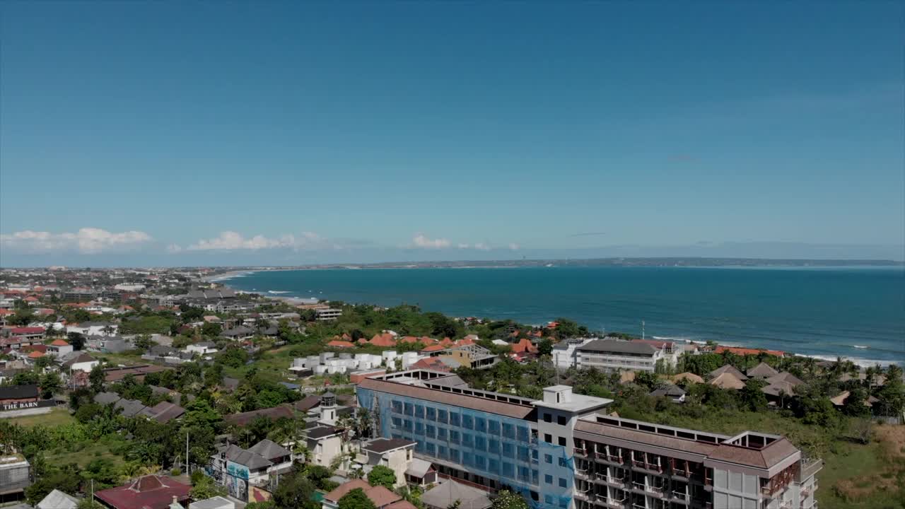 航拍全景巴厘村沧古在海湾与传统瓦屋顶和大量的绿色植物在阳光明媚的日子。视频下载